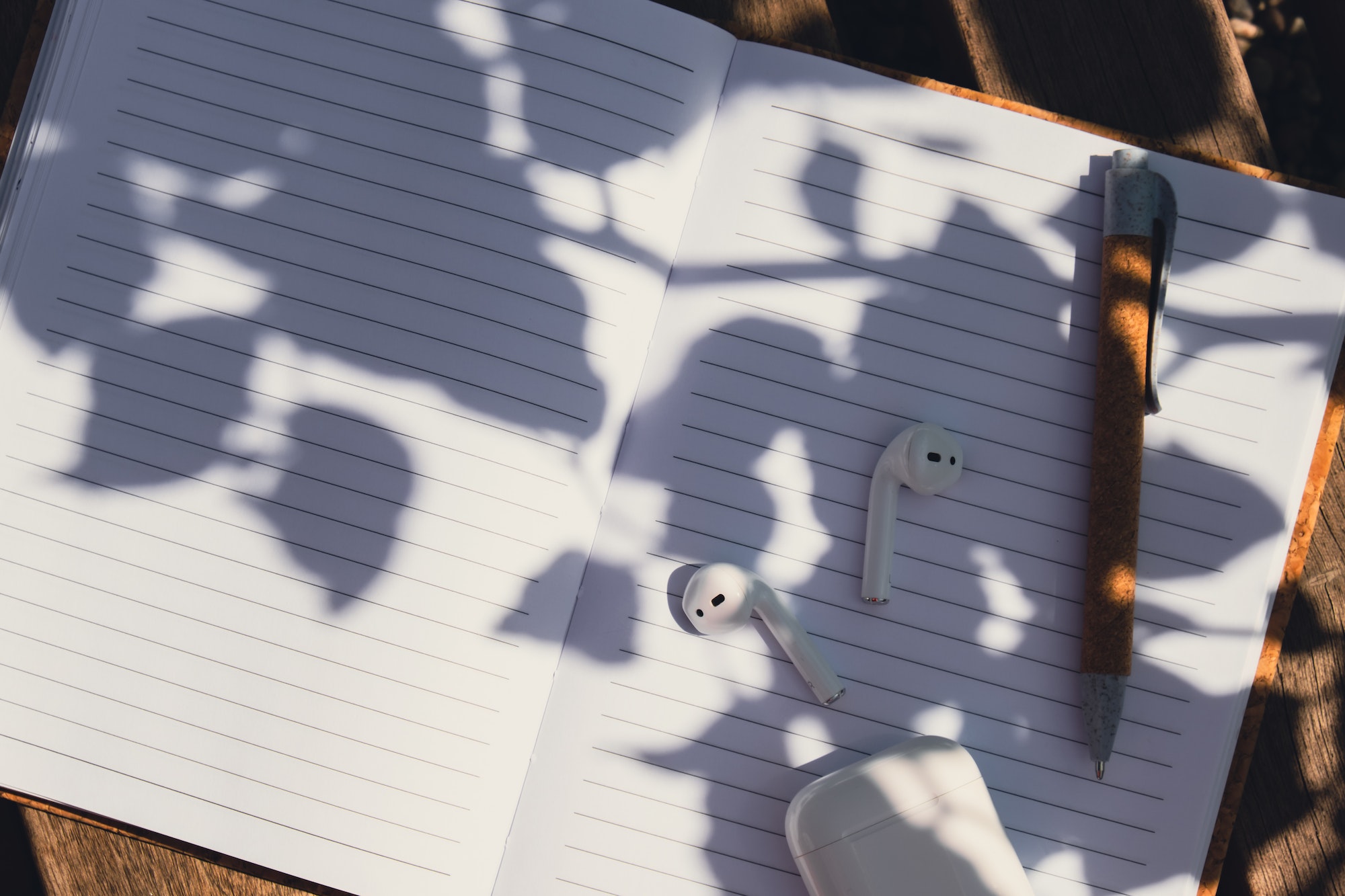 Paper notebook with wireless headphones. Mockup Coffee break. Audio healing, sound therapy wellness